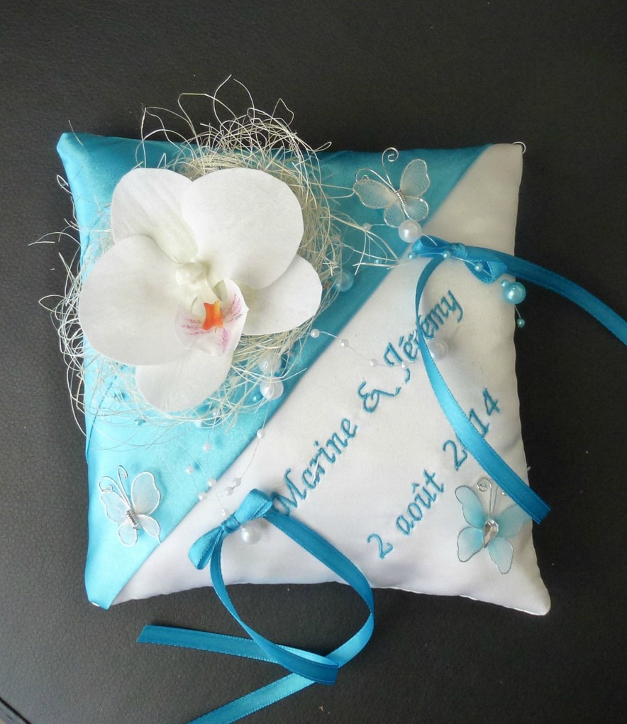 Ref:5-N
Coussin d'alliance bleu turquoise et blanc orchidée
Porte alliance Mariage thème orchidée papillon
Perles,rafia 
Broderie
Coussin 19x19cm
39€
