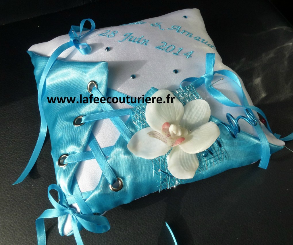 Ref: 5-A
Coussin d'alliance blanc et bleu turquoise forme corset 
19x19cm
Mariage thème orchidée
Strass et broderie
38€